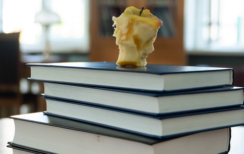 Image of pile of books with a half-eaten apple resting on top